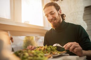 Young happy man enjoying in a healthy meal.