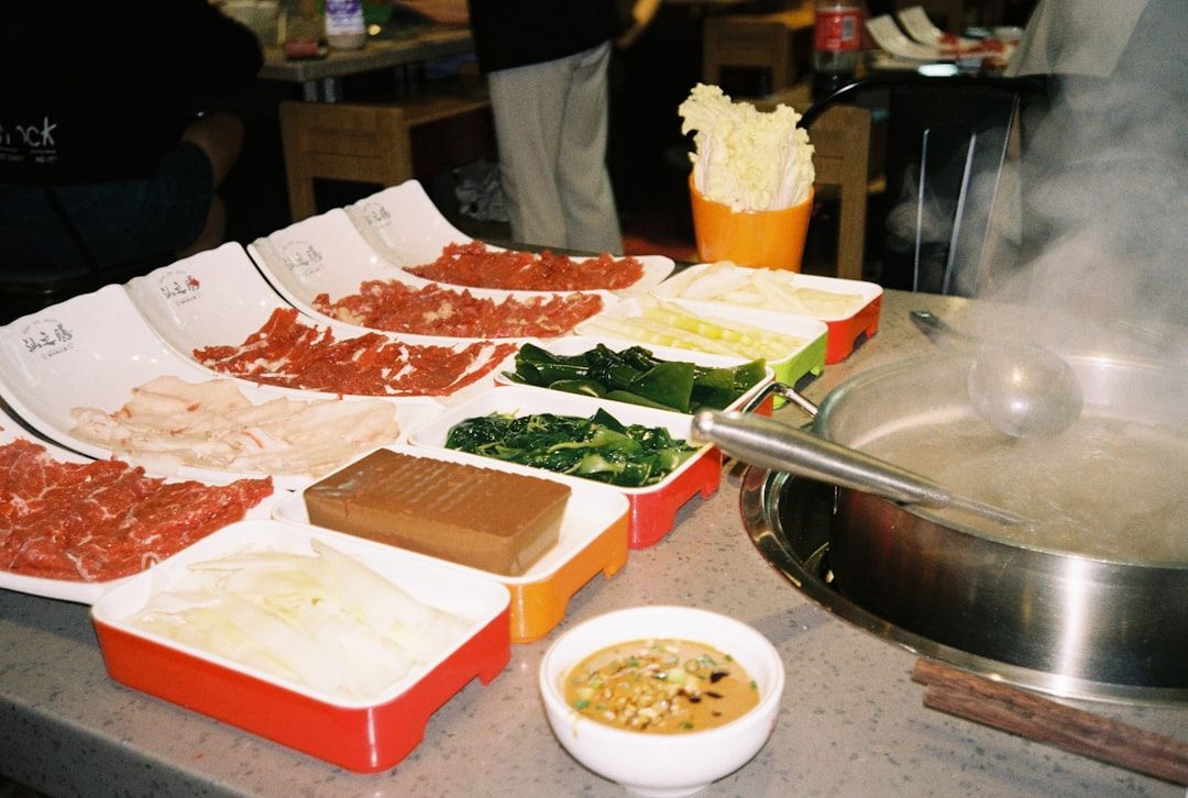 En hot pot-måltid med råa ingredienser upplagda bredvid en ångande gryta.